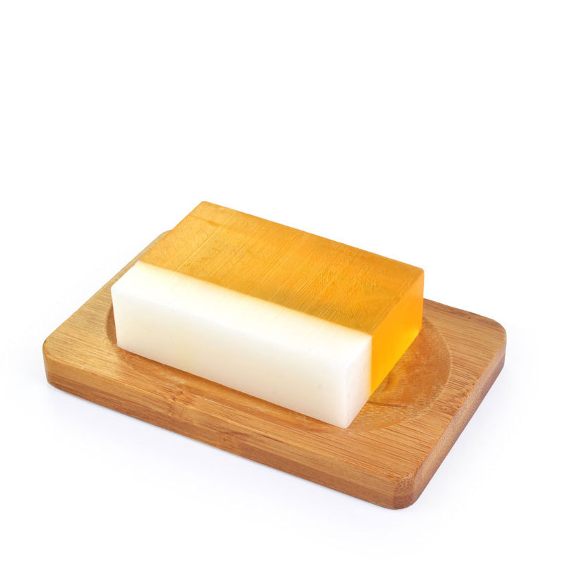 Honey - A dual-layered soap bar, with a clear amber top and a white bottom, rests on a wooden tray against a plain white background, conveying simplicity.